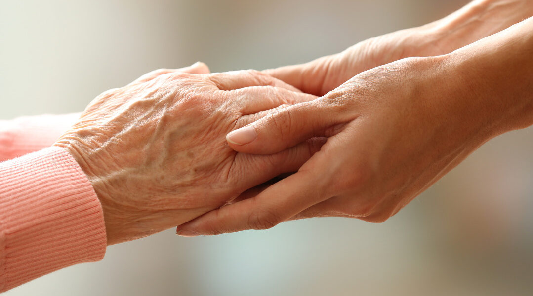 Hand of an elderly person and a younger person together